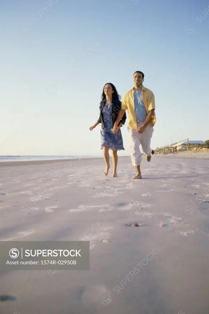 Low angle view of a young couple running together on the beach