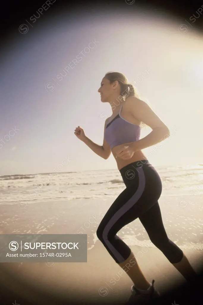 Side profile of a young woman jogging at the beach