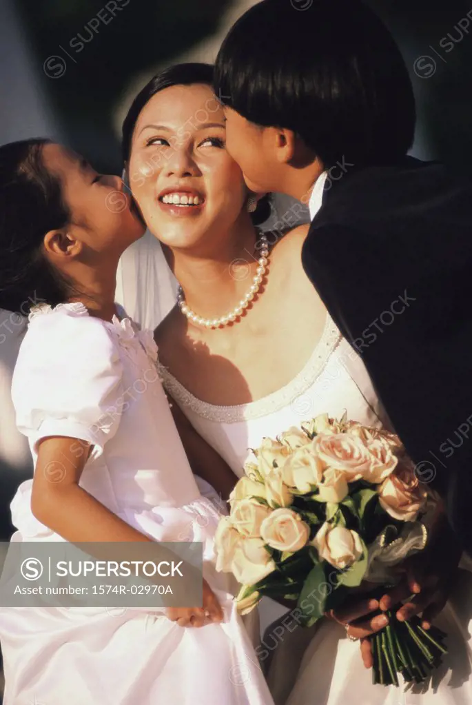 Flower girl and ring bearer kissing a bride