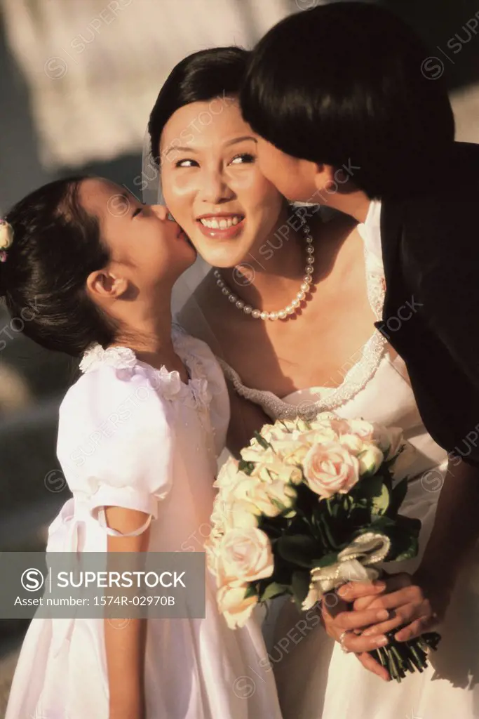 Flower girl and ring bearer kissing a bride