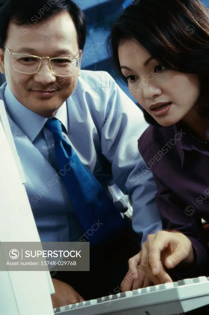 Businessman and a businesswoman sitting in front of a computer