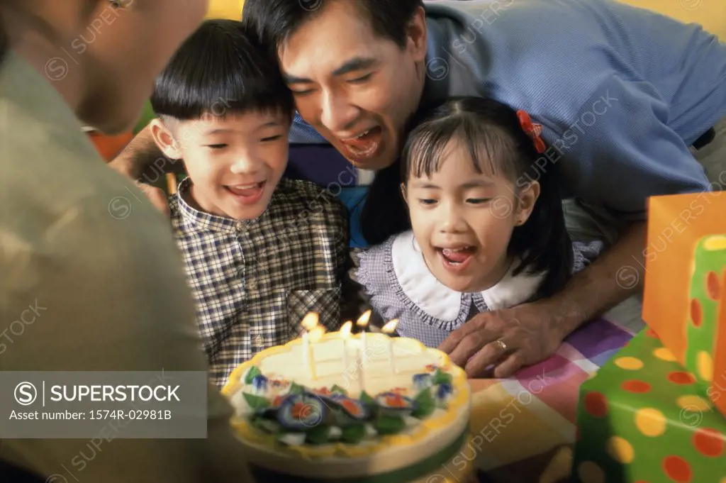 Son and daughter in front of a birthday cake with their parents