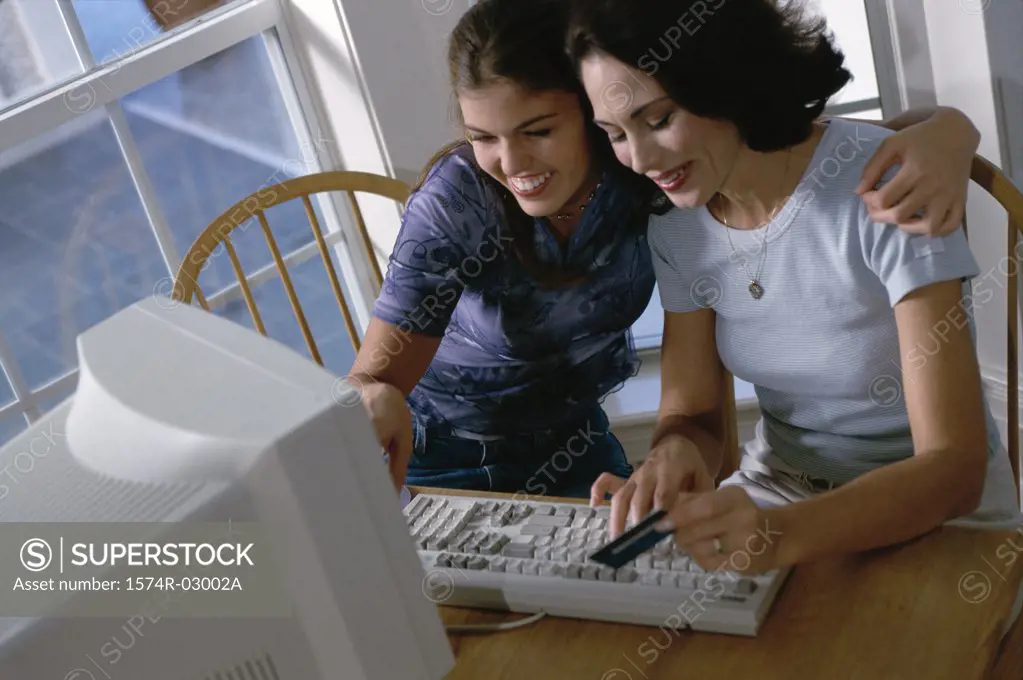 Mother and her daughter sitting in front of a computer