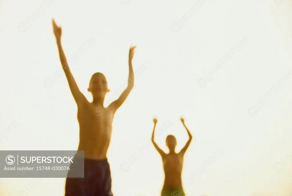 Front view of two boys standing with their arms raised