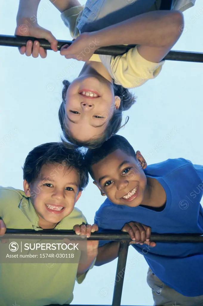 Close-up of two boys and a girl playing on monkey bars