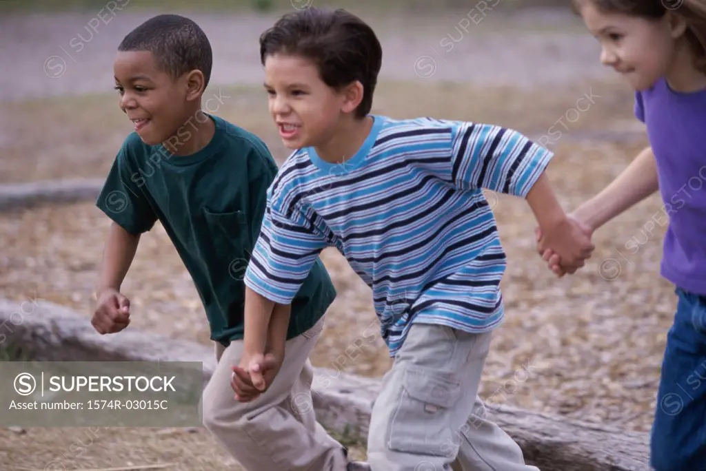 Two boys and a girl running holding hands