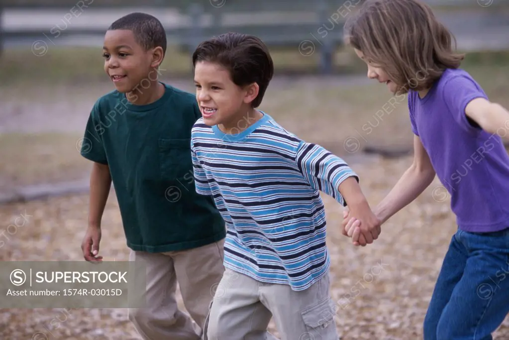 Two boys and a girl running holding hands