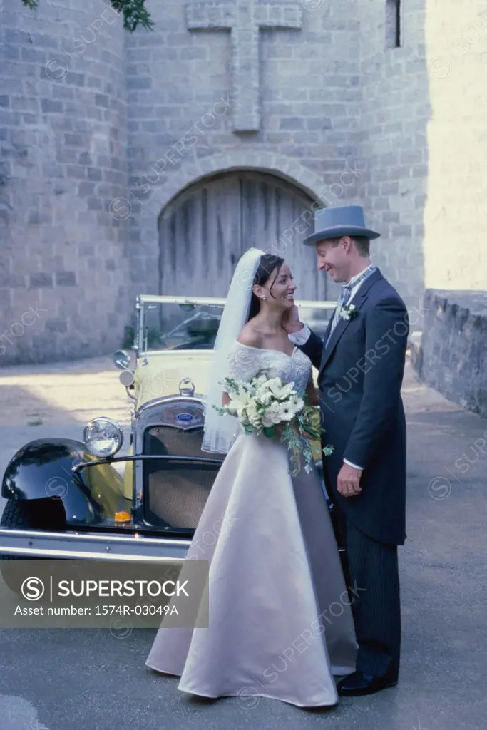 Newlywed couple standing in front of an antique car
