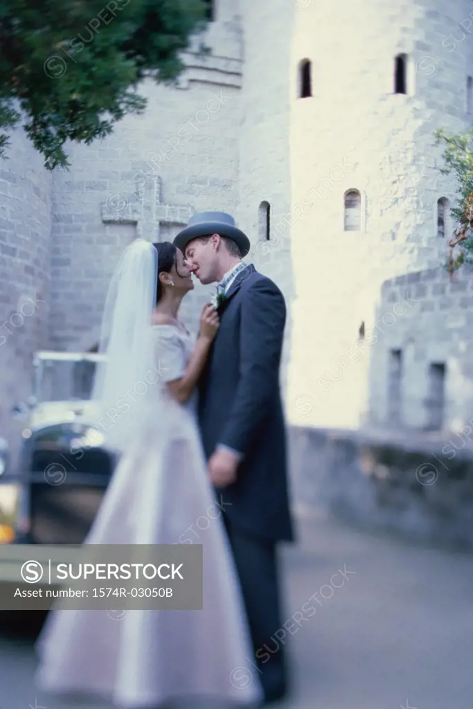 Newlywed couple kissing each other in front of an antique car