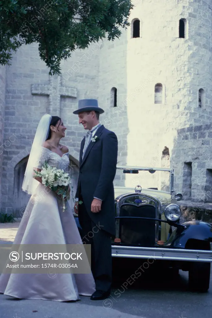 Newlywed couple standing in front of an antique car