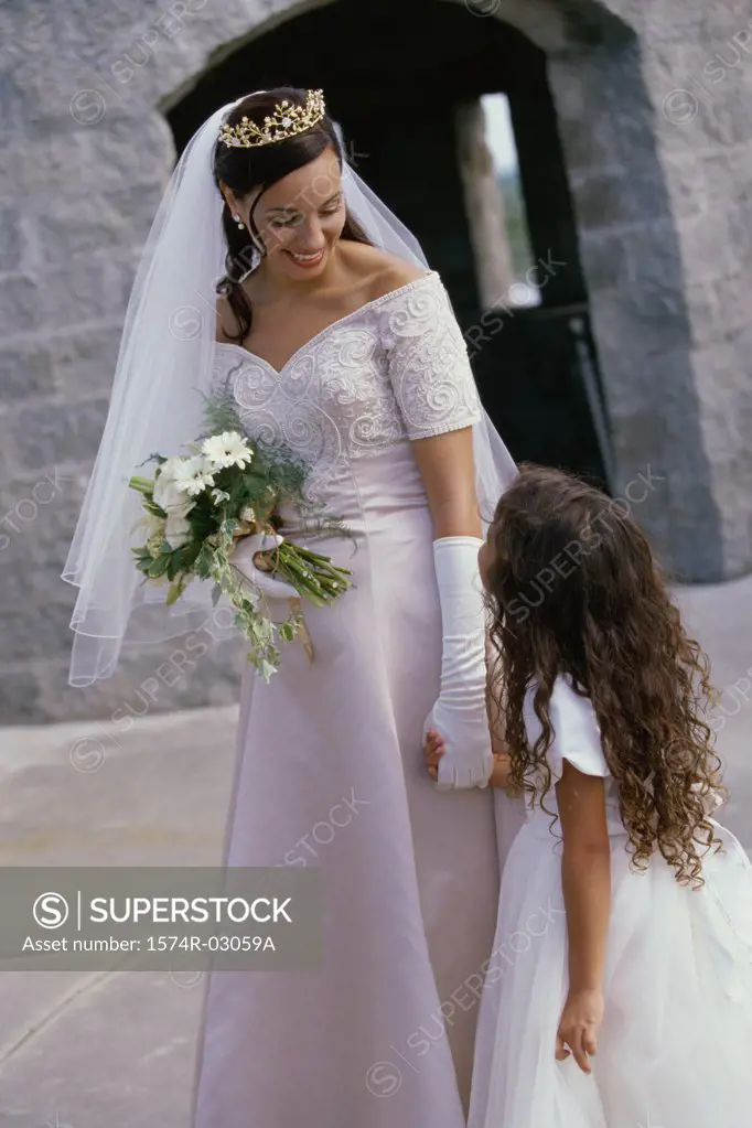 Bride holding a bouquet of flowers talking to a flower girl