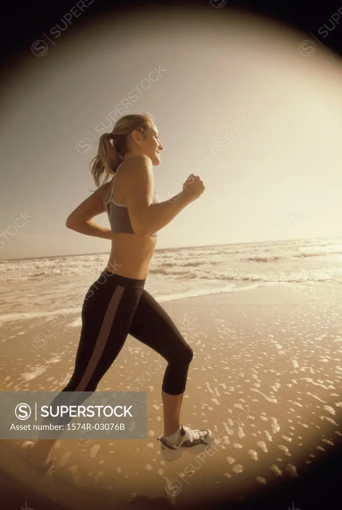 Side profile of a young woman jogging on the beach