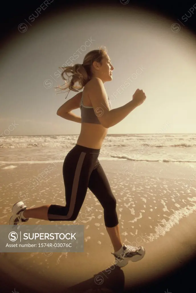 Side profile of a young woman jogging on the beach