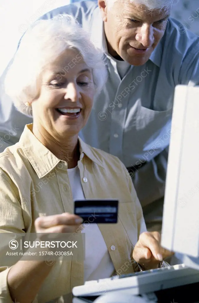 Senior couple in front of a computer holding a credit card