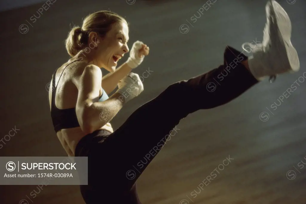 Side profile of a young woman kickboxing