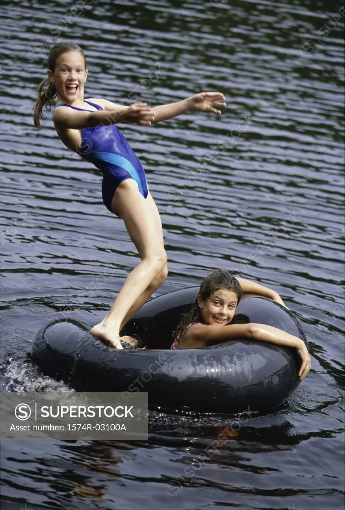 Portrait of two girls playing in water with inner tube