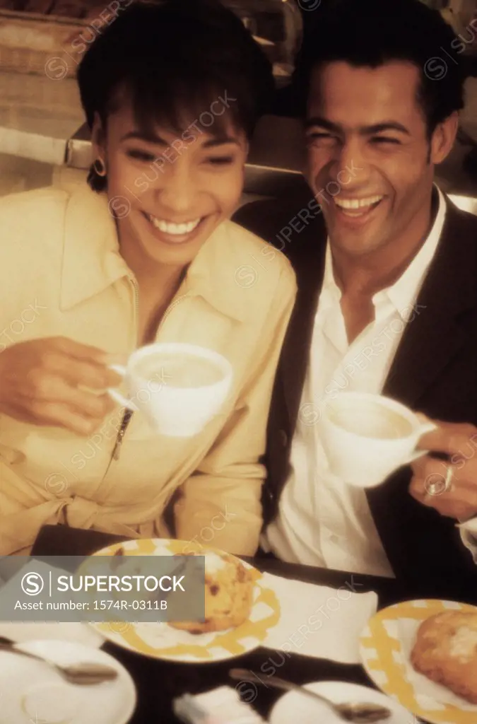 Smiling young couple holding cups of coffee