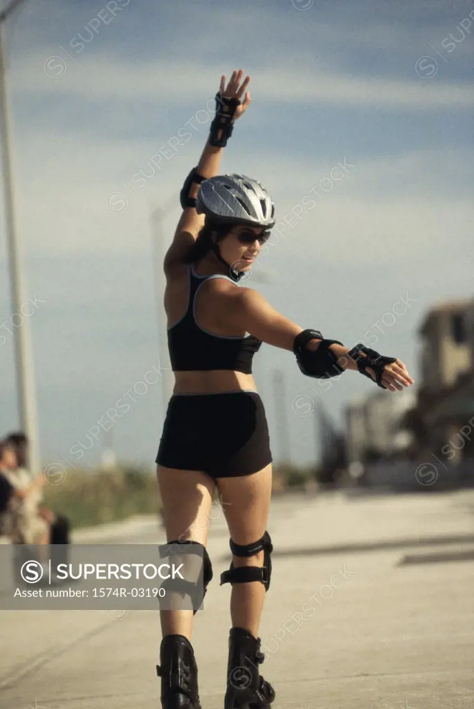 Rear view of a young woman inline skating on a road