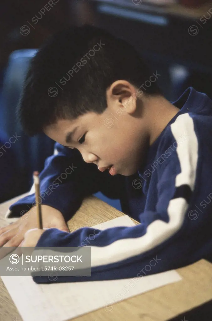 Boy writing on a paper with a pencil