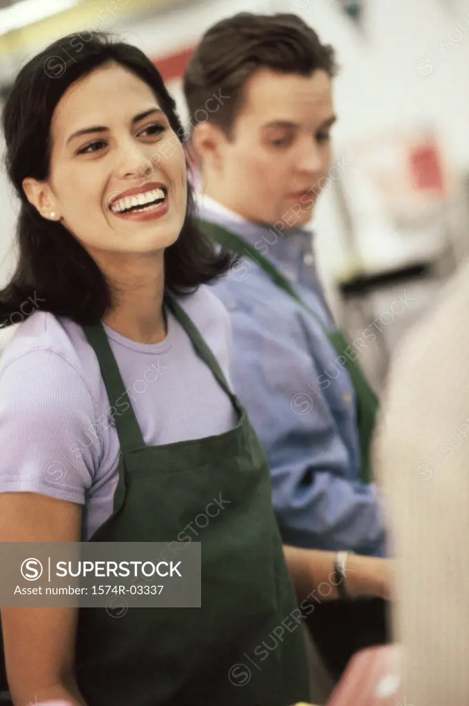 Female sales clerk standing at a checkout counter in a supermarket