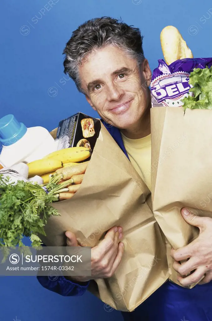 Portrait of a mature man carrying two grocery bags