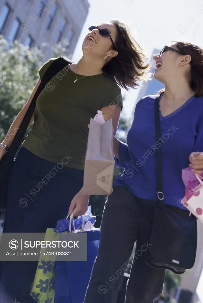 Low angle view of two young women carrying shopping bags