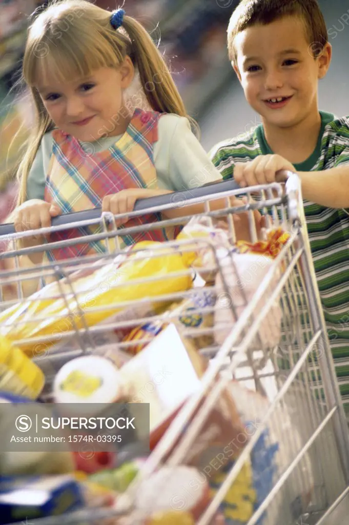 Girl and a boy playing with a shopping cart in a supermarket