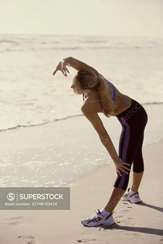 Side profile of a young woman exercising on the beach