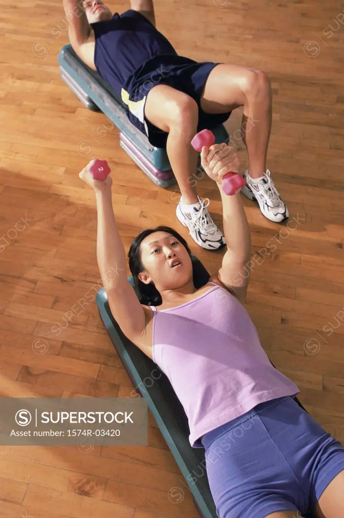 Young woman and a young man exercising with dumbbells in a health club