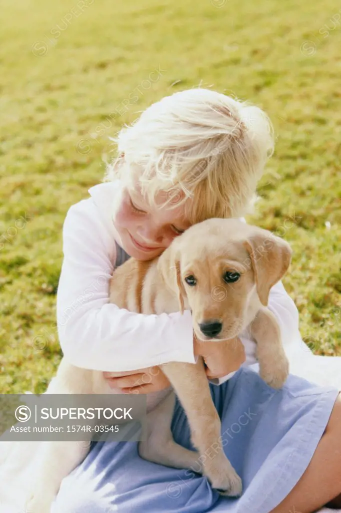 Girl sitting on a lawn holding a puppy