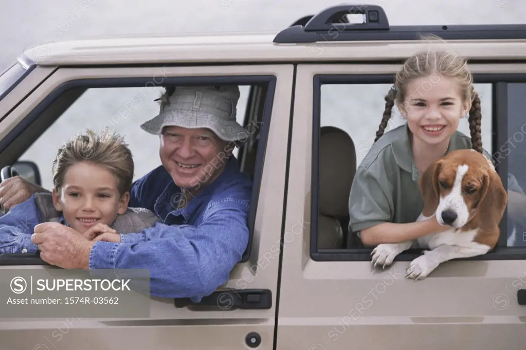 Portrait of a grandfather smiling with his grandson and granddaughter in a car