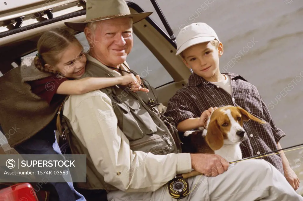 Portrait of a grandfather with his grandson and granddaughter holding a fishing rod
