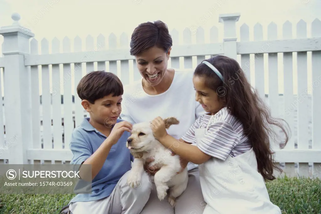 Mother with her son and daughter petting a puppy