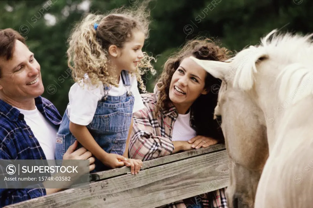 Parents with their daughter in front of a horse
