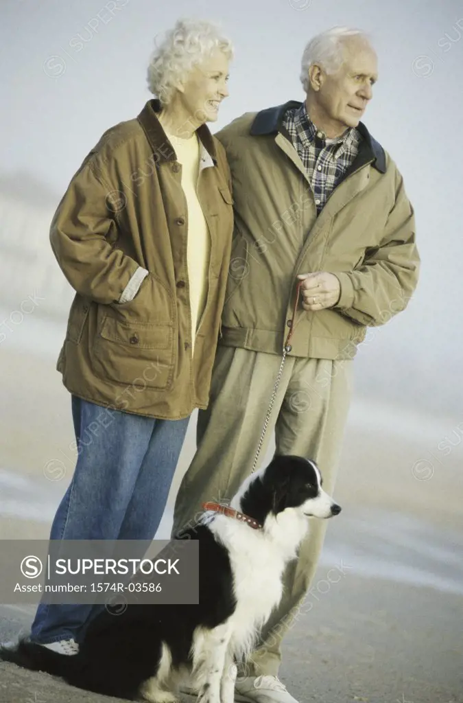 Senior couple standing with their dog on the beach