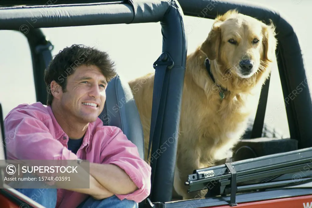 Mid adult man sitting in a jeep with his dog