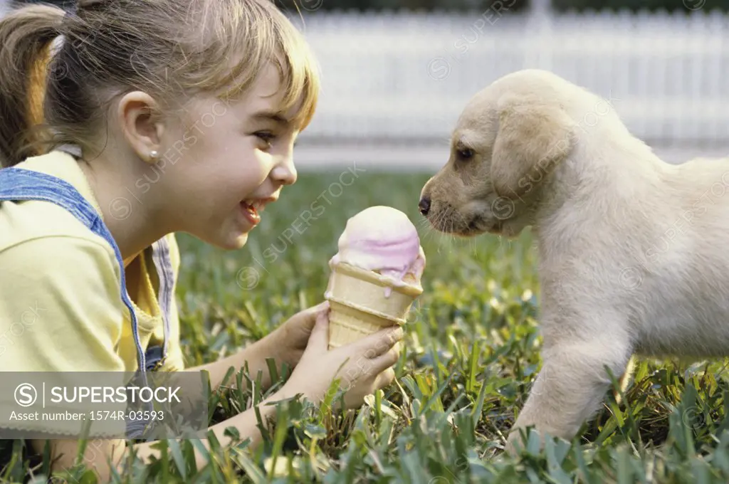 Side profile of a girl holding an ice cream cone in front of a puppy