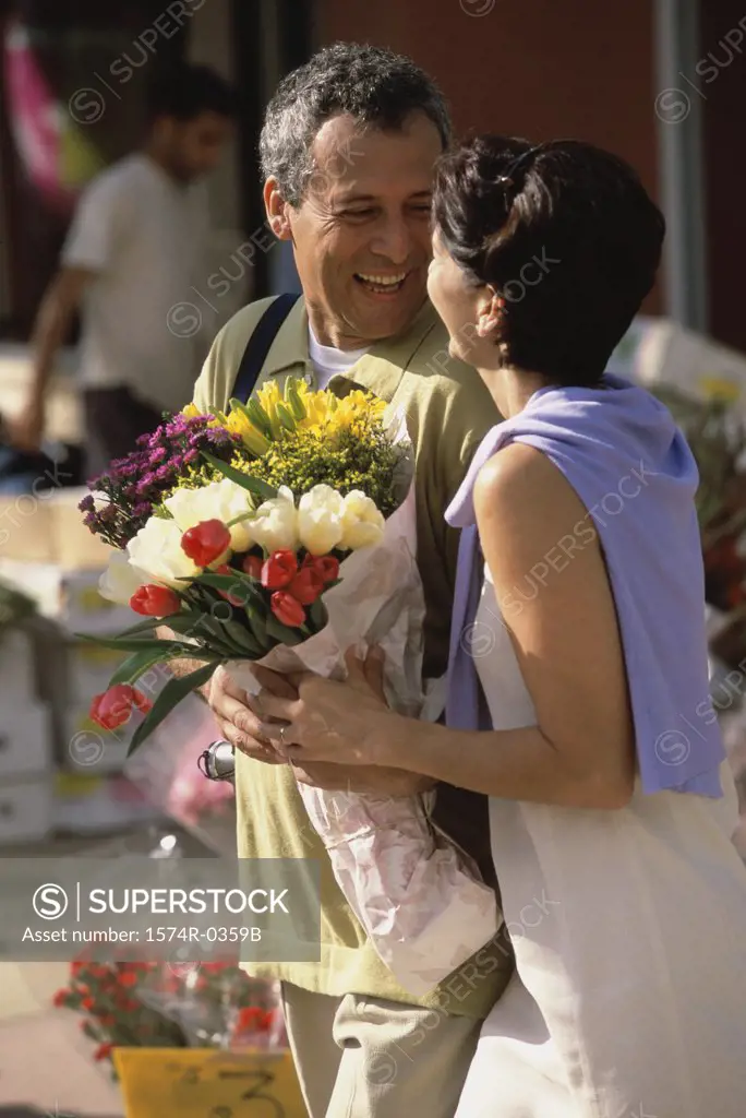 Couple smiling holding a bouquet of flowers