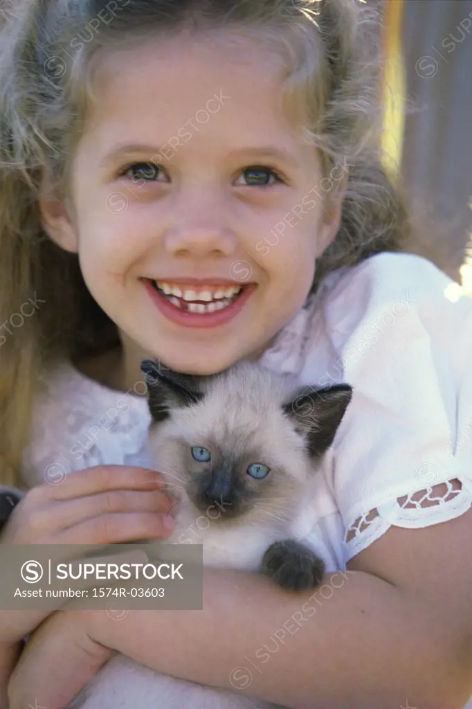 Close-up of a girl holding a Siamese kitten