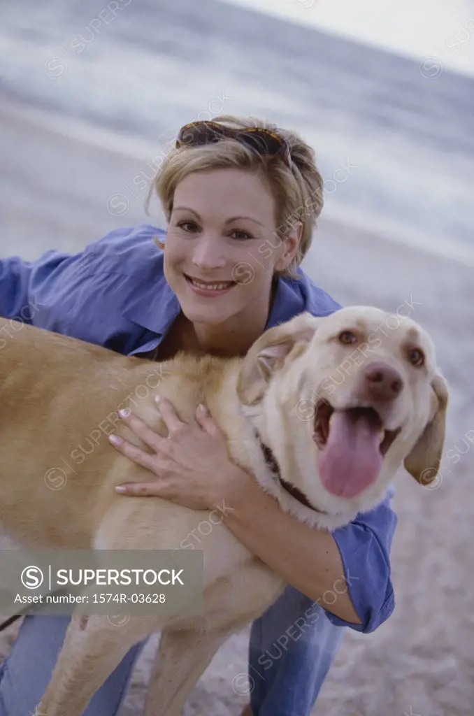 Portrait of a young woman holding her dog on the beach