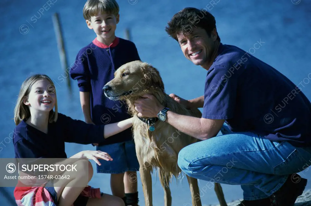 Father and his son and daughter playing with their dog