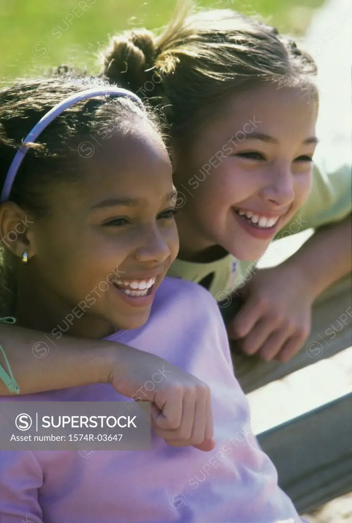 Two girls sitting on a bench smiling