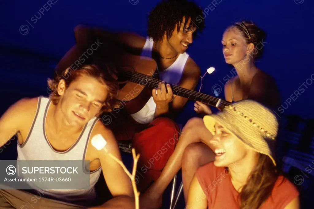 Young couple roasting marshmallows on the beach
