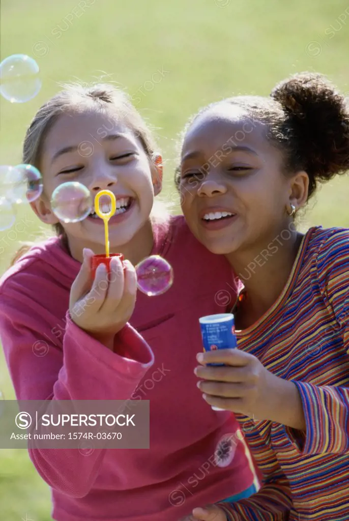 Close-up of two girls blowing bubbles