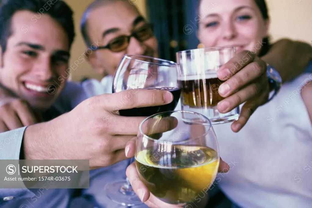 Two young men and a young woman toasting with wineglasses in a restaurant