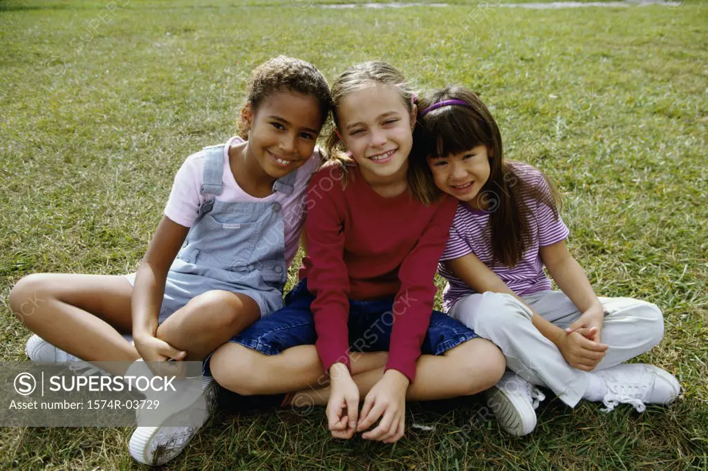Portrait of three girls sitting on a lawn