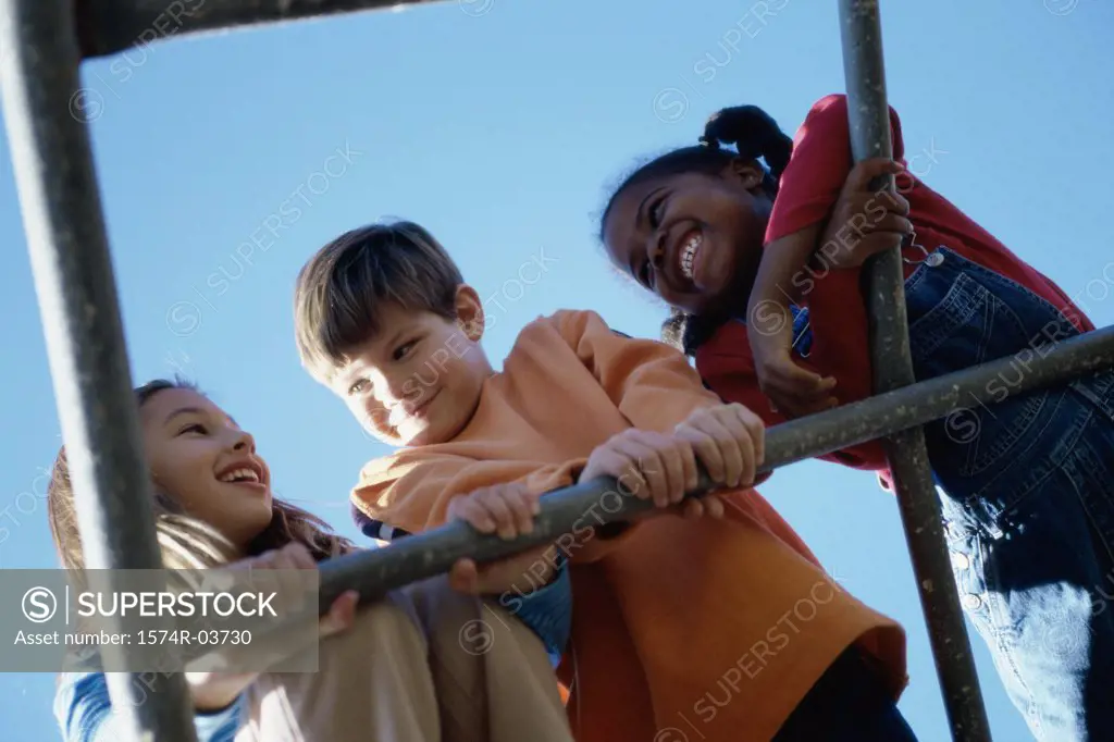 Low angle view of three children playing on a monkey bars