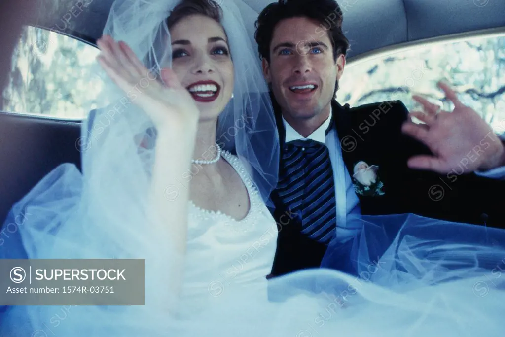 Newlywed couple waving from inside a car