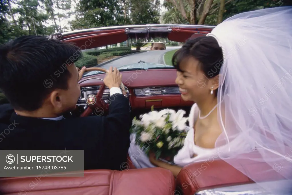 Newlywed couple talking to each other in a convertible car