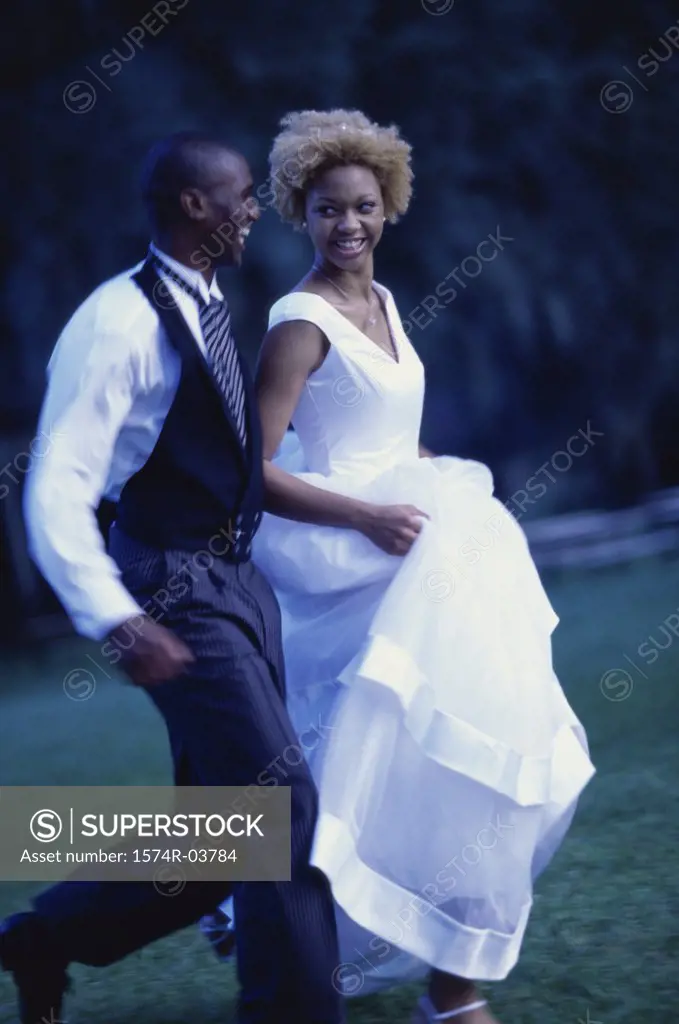 Side profile of a newlywed couple running on a lawn